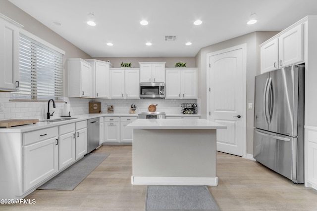 kitchen featuring a center island, white cabinetry, sink, and appliances with stainless steel finishes