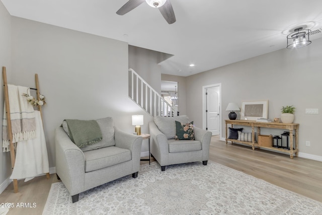 living room with light hardwood / wood-style floors and ceiling fan with notable chandelier