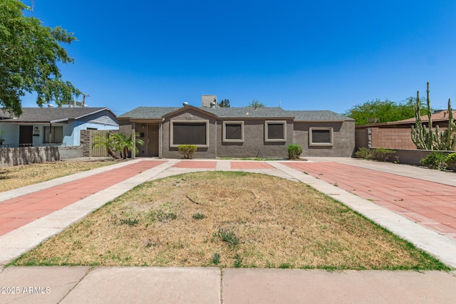 view of front of home with fence, a front lawn, and stucco siding