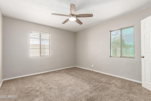carpeted empty room featuring baseboards and a ceiling fan