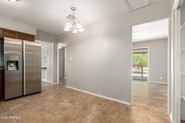 kitchen with brown cabinets, a chandelier, baseboards, stainless steel fridge, and hanging light fixtures