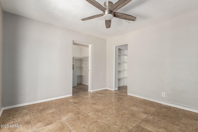 unfurnished bedroom with a closet, ceiling fan, a walk in closet, visible vents, and baseboards