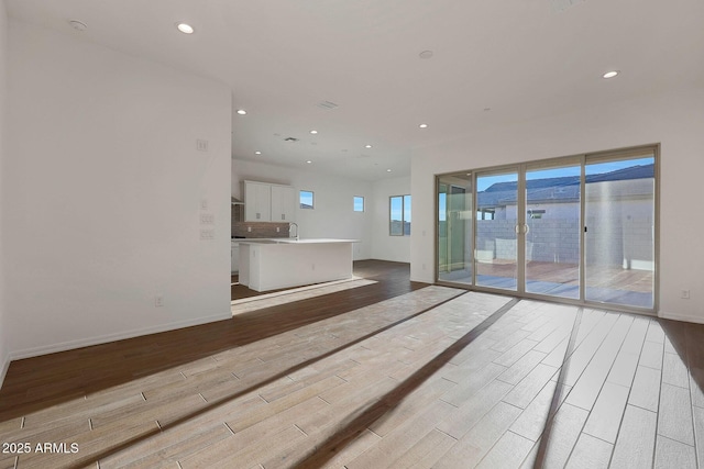 unfurnished living room with sink and light hardwood / wood-style flooring