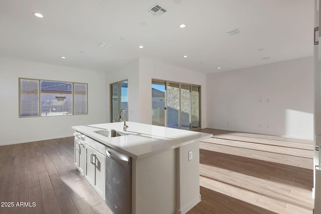 kitchen with sink, light hardwood / wood-style floors, white cabinets, a center island with sink, and stainless steel dishwasher