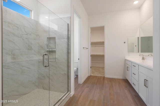 bathroom featuring hardwood / wood-style flooring, vanity, toilet, and a shower with shower door