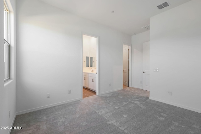 unfurnished bedroom featuring light colored carpet and ensuite bath