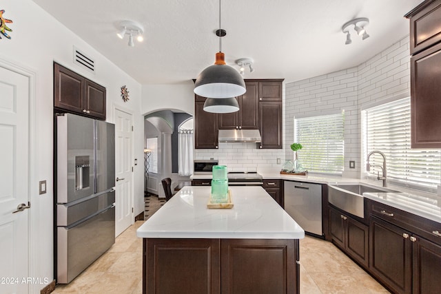 kitchen with hanging light fixtures, a center island, stainless steel appliances, sink, and dark brown cabinets