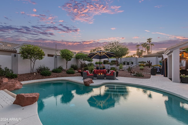 pool at dusk featuring an outdoor living space and a patio