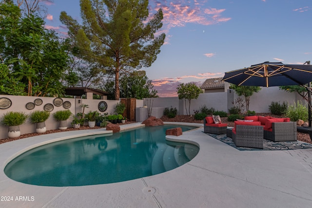 pool at dusk with an outdoor hangout area and a patio area