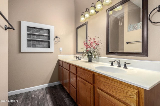 full bathroom featuring double vanity, baseboards, a sink, and wood finished floors