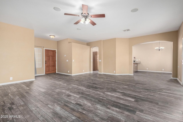 unfurnished living room featuring arched walkways, ceiling fan with notable chandelier, visible vents, baseboards, and dark wood-style floors