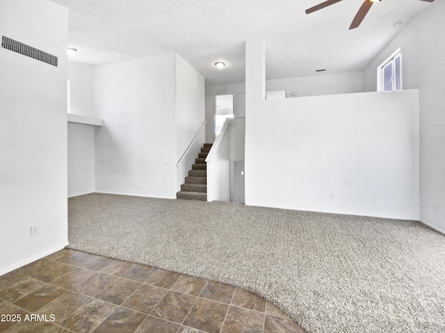 interior space with dark colored carpet, visible vents, ceiling fan, and stairway