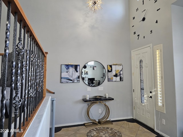 entrance foyer featuring a high ceiling, a healthy amount of sunlight, an inviting chandelier, and light tile patterned flooring