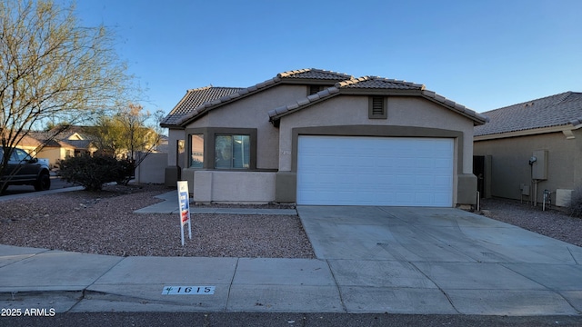 view of front facade with a garage, concrete driveway, a tile roof, and stucco siding