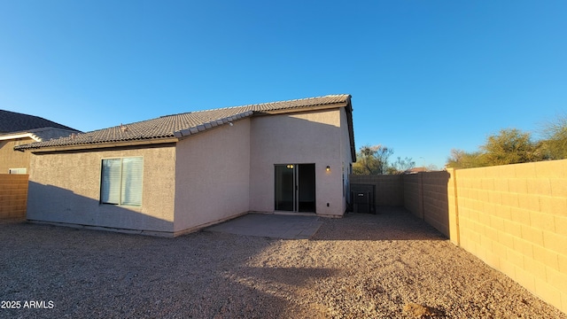 rear view of property with a patio area, a fenced backyard, a tile roof, and stucco siding