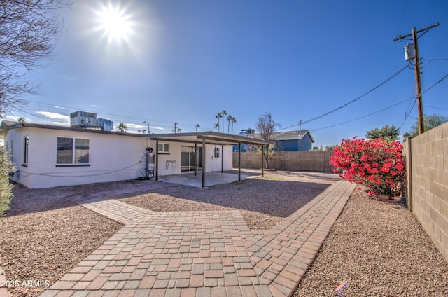 rear view of property with cooling unit and a patio