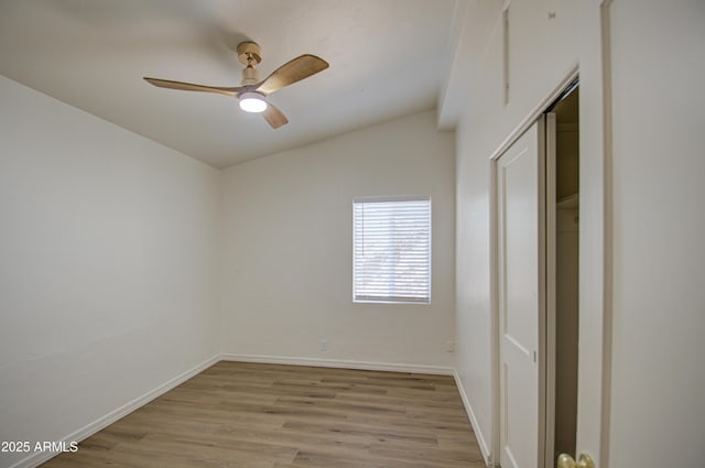 empty room with ceiling fan, light hardwood / wood-style flooring, and vaulted ceiling