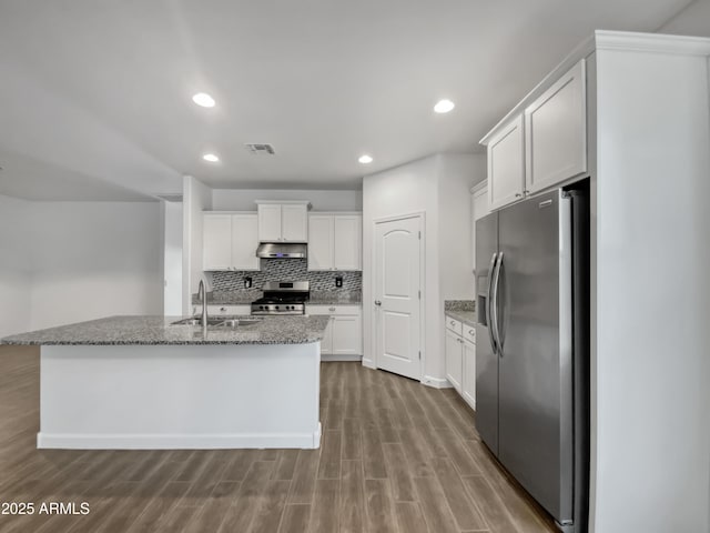 kitchen with stone counters, sink, stainless steel appliances, a kitchen island with sink, and white cabinets