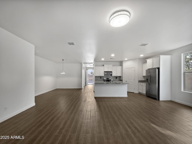 kitchen with dark hardwood / wood-style floors, stainless steel fridge, white cabinetry, and an island with sink