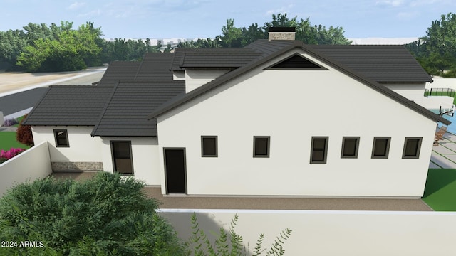 exterior space featuring stucco siding, a chimney, and fence