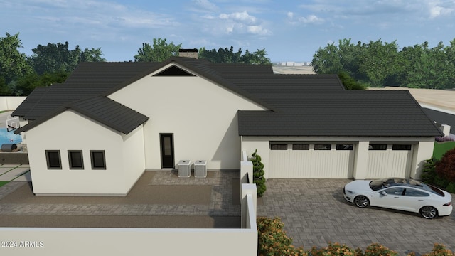 view of front of house featuring a chimney, a garage, driveway, and stucco siding