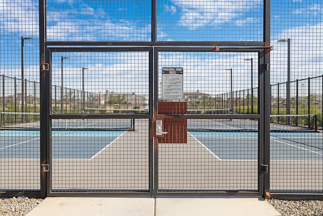 view of basketball court featuring fence, a tennis court, and a gate