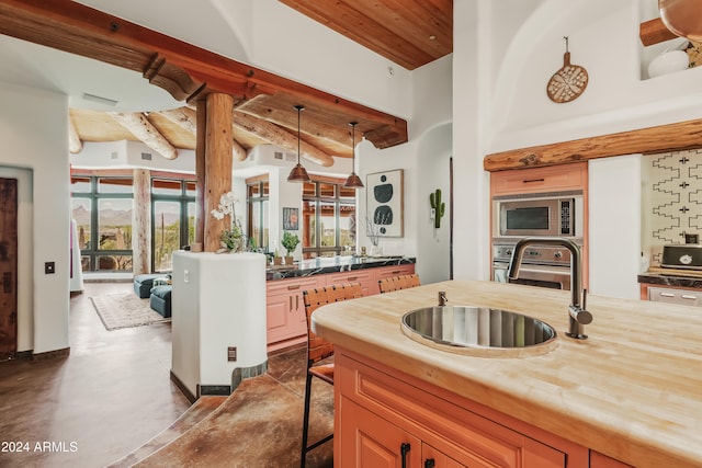 kitchen featuring concrete floors, stainless steel appliances, plenty of natural light, and hanging light fixtures