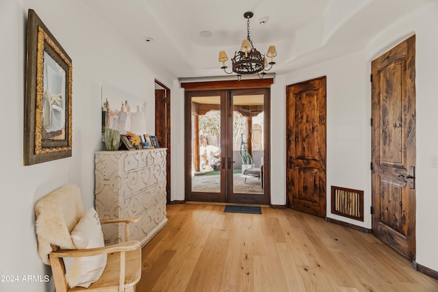 doorway to outside featuring french doors, an inviting chandelier, and light wood-type flooring