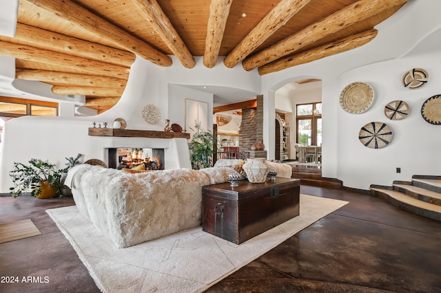 living room with beam ceiling, wooden ceiling, a multi sided fireplace, and concrete floors