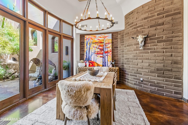 dining area with brick wall, a chandelier, and a towering ceiling