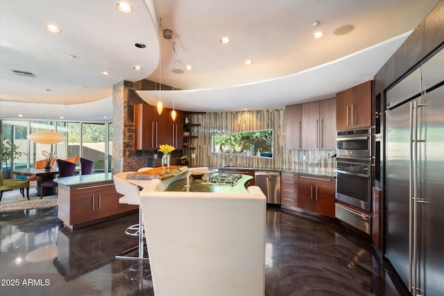 kitchen with a breakfast bar area, tasteful backsplash, a kitchen island, pendant lighting, and stainless steel appliances