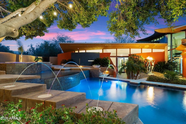 pool at dusk featuring pool water feature