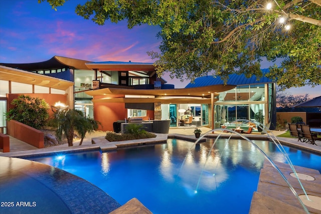 pool at dusk featuring a patio and pool water feature