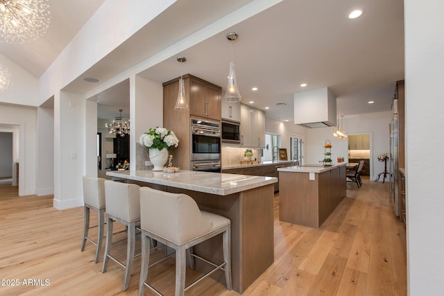 2737 E Arizona Biltmore Cir Unit 8, Phoenix, AZ 85016 - kitchen featuring a chandelier, double oven, black microwave, light wood-style flooring, and a breakfast bar