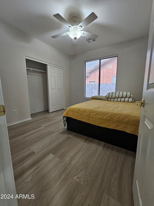 bedroom with hardwood / wood-style flooring, ceiling fan, and a closet