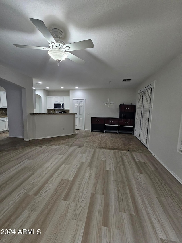 unfurnished living room featuring hardwood / wood-style floors and ceiling fan