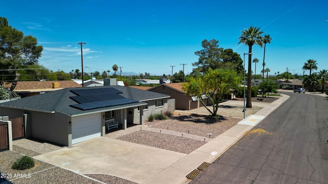 view of front of house featuring an attached garage, stucco siding, a shingled roof, concrete driveway, and roof mounted solar panels