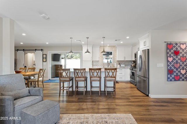 kitchen with stainless steel appliances, a kitchen breakfast bar, open floor plan, white cabinets, and tasteful backsplash