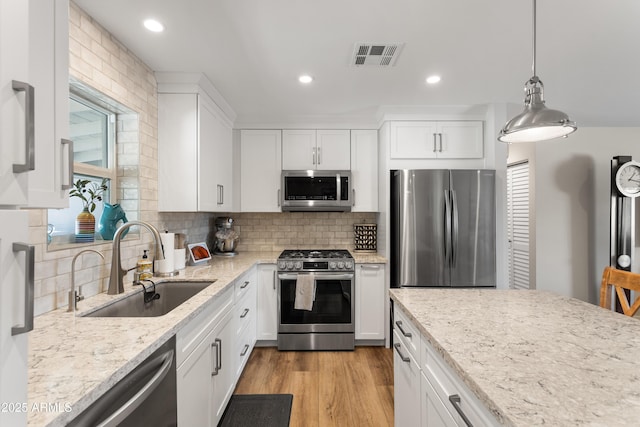 kitchen featuring white cabinetry, appliances with stainless steel finishes, visible vents, and a sink