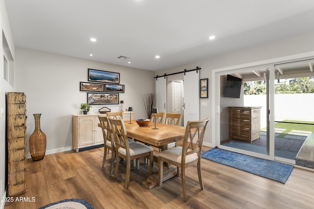 dining space with light wood-style flooring, a barn door, visible vents, and recessed lighting