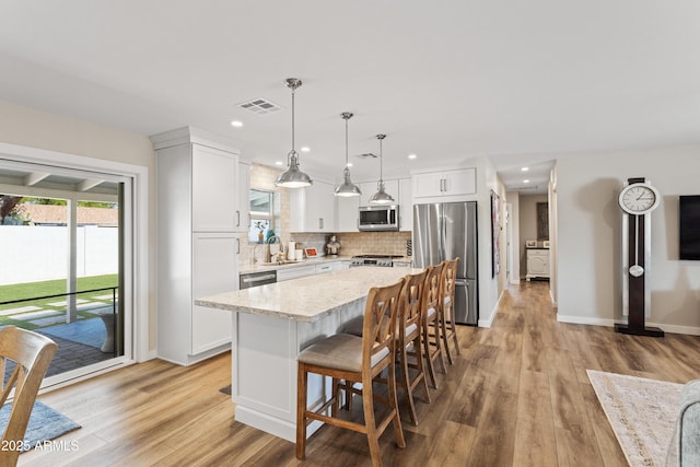 kitchen featuring a sink, visible vents, decorative backsplash, a center island, and appliances with stainless steel finishes