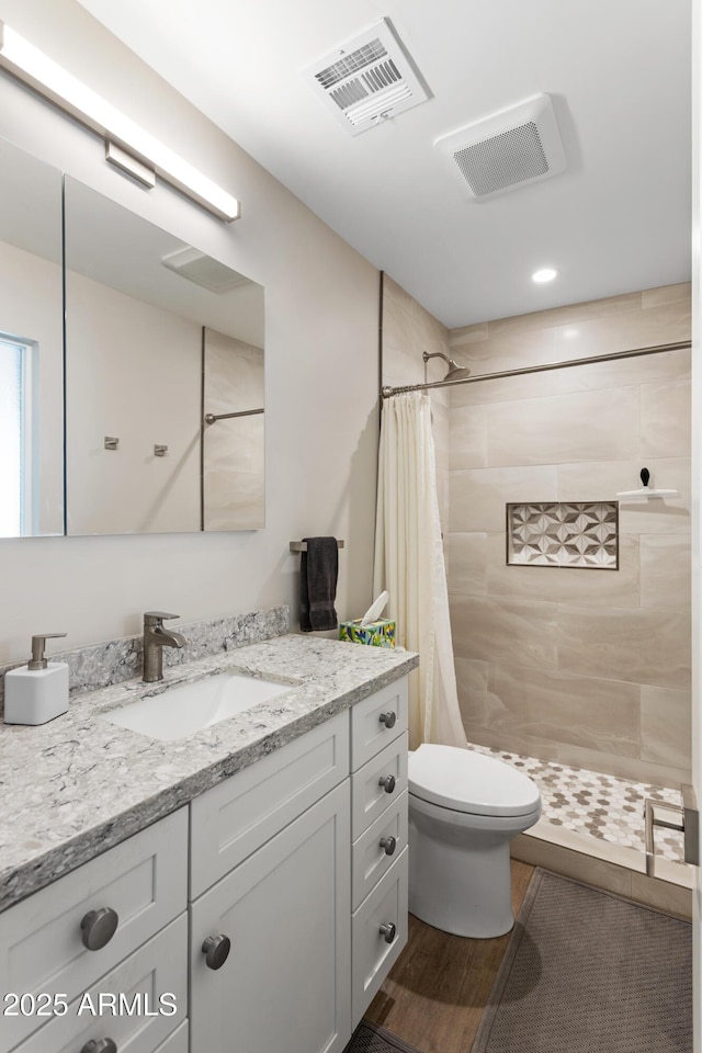 bathroom with toilet, visible vents, and a tile shower
