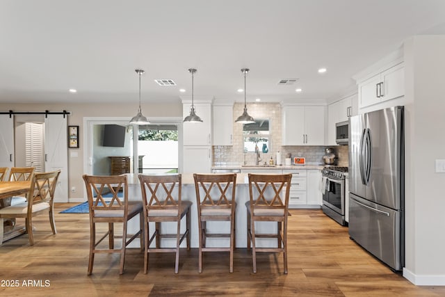 kitchen featuring a kitchen island, stainless steel appliances, a barn door, and visible vents