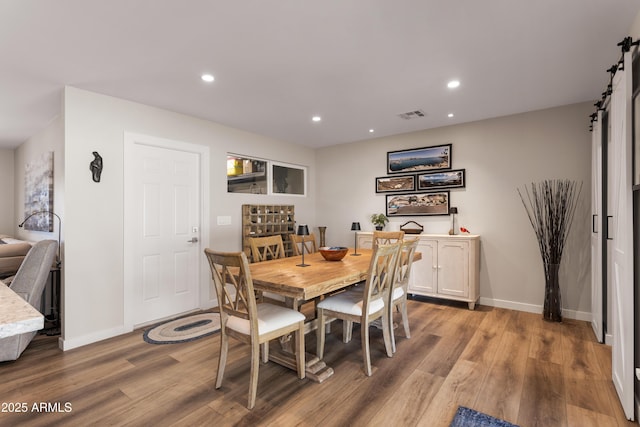 dining area with recessed lighting, a barn door, baseboards, light wood finished floors, and visible vents