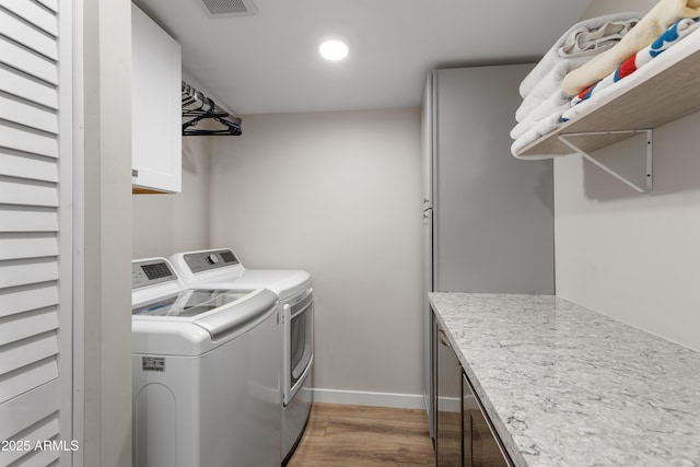 laundry area with wood finished floors, cabinet space, visible vents, baseboards, and independent washer and dryer