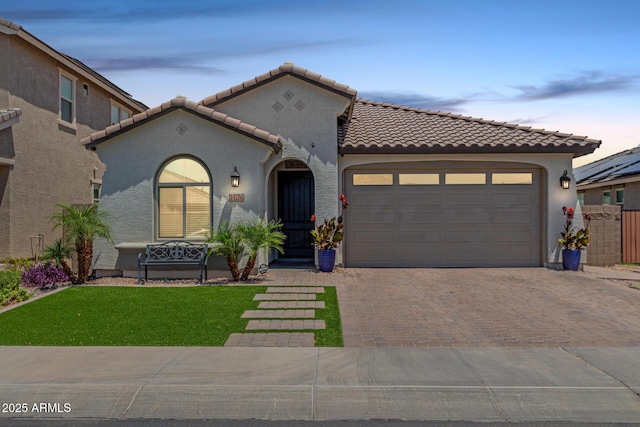 15276 W Latham St, Goodyear, AZ 85338 - mediterranean / spanish house with decorative driveway, a tile roof, a garage, and stucco siding
