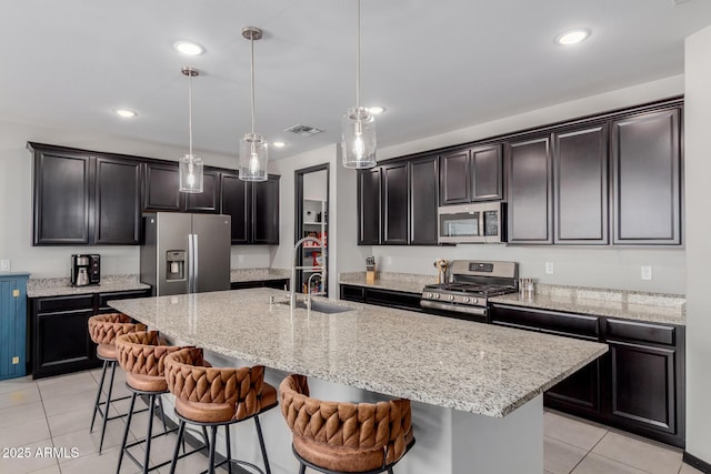15276 W Latham St, Goodyear, AZ 85338 - kitchen with appliances with stainless steel finishes, light tile patterned floors, a breakfast bar, a kitchen island with sink, and recessed lighting