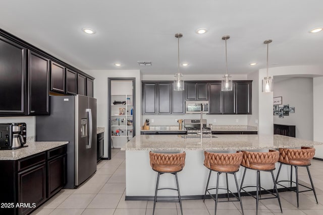 15276 W Latham St, Goodyear, AZ 85338 - kitchen featuring stainless steel appliances, a kitchen breakfast bar, light stone counters, pendant lighting, and light tile patterned flooring