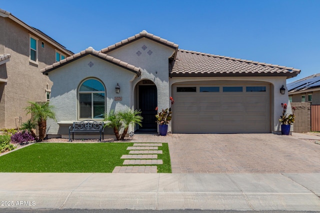 15276 W Latham St, Goodyear, AZ 85338 - mediterranean / spanish-style house featuring a tile roof, stucco siding, decorative driveway, and an attached garage