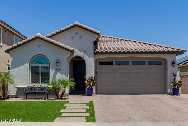 15276 W Latham St, Goodyear, AZ 85338 - mediterranean / spanish-style house featuring a tiled roof, decorative driveway, stucco siding, and an attached garage